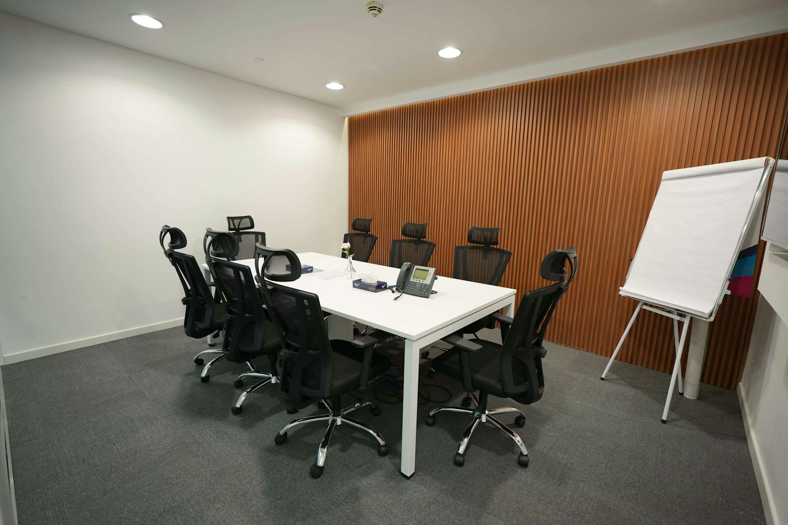 Institutional meeting room with conference table, ergonomic chairs, and presentation board